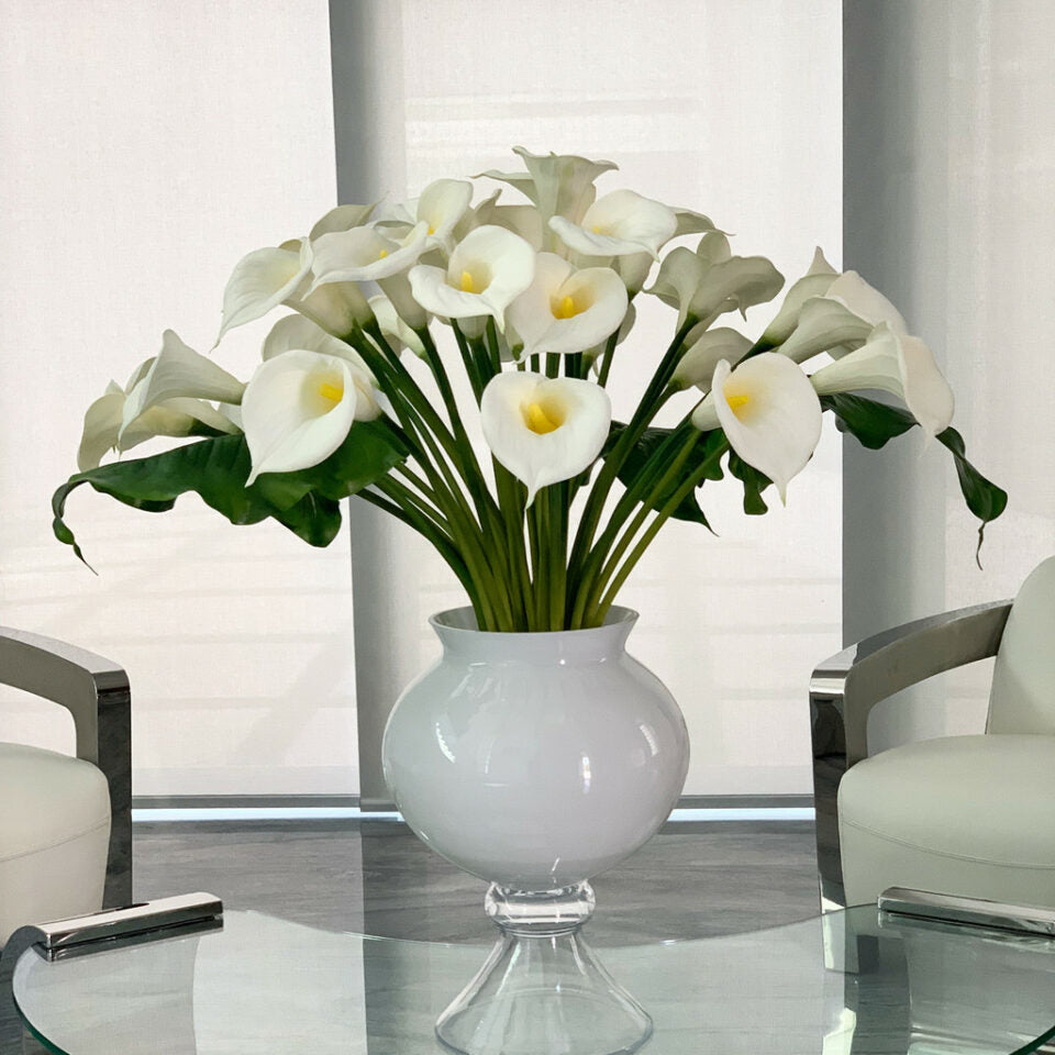 Vase élégant avec plusieurs arums blancs